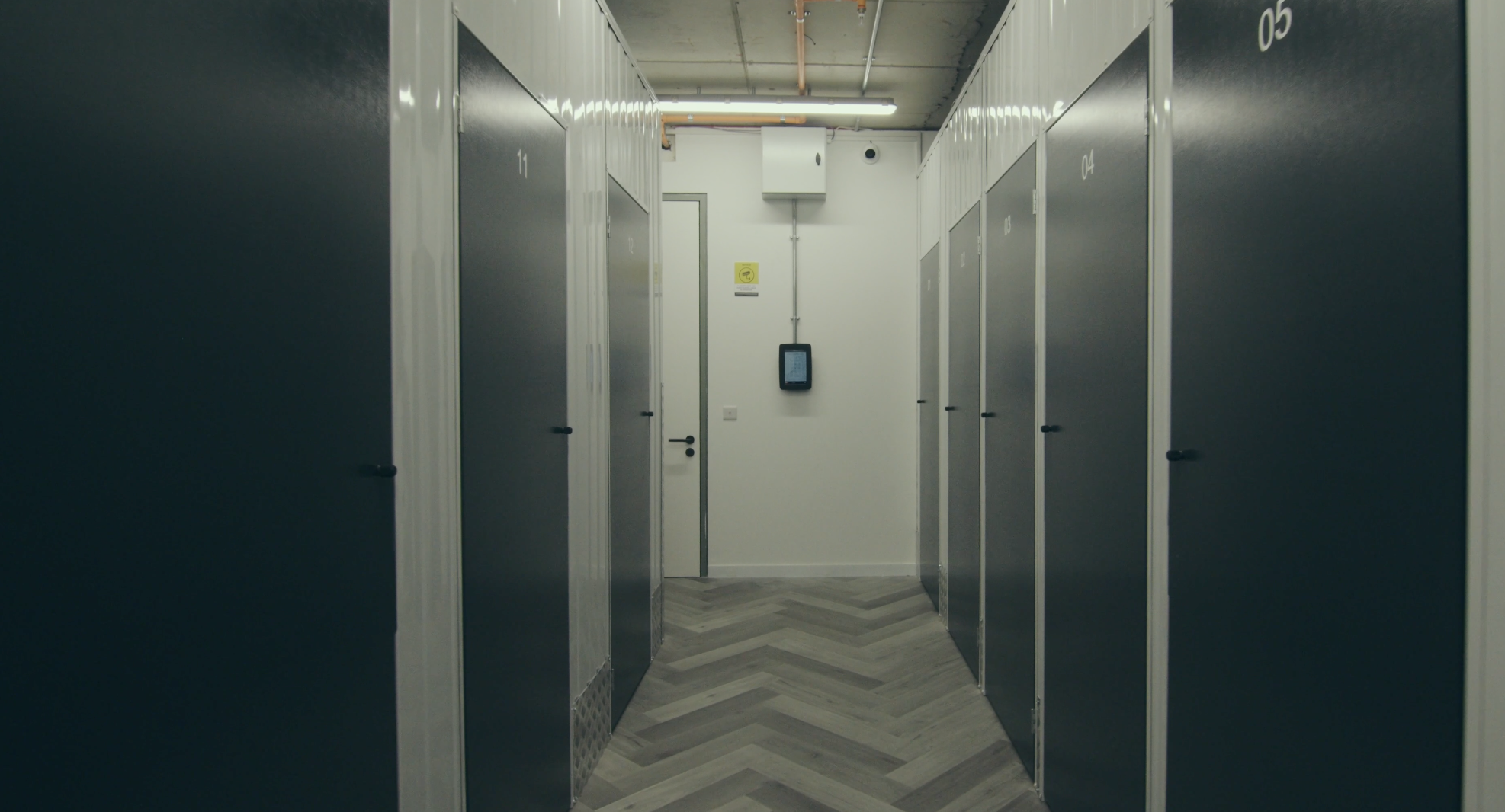 Self-storage units lining a secure facility corridor with a wall-mounted access terminal
